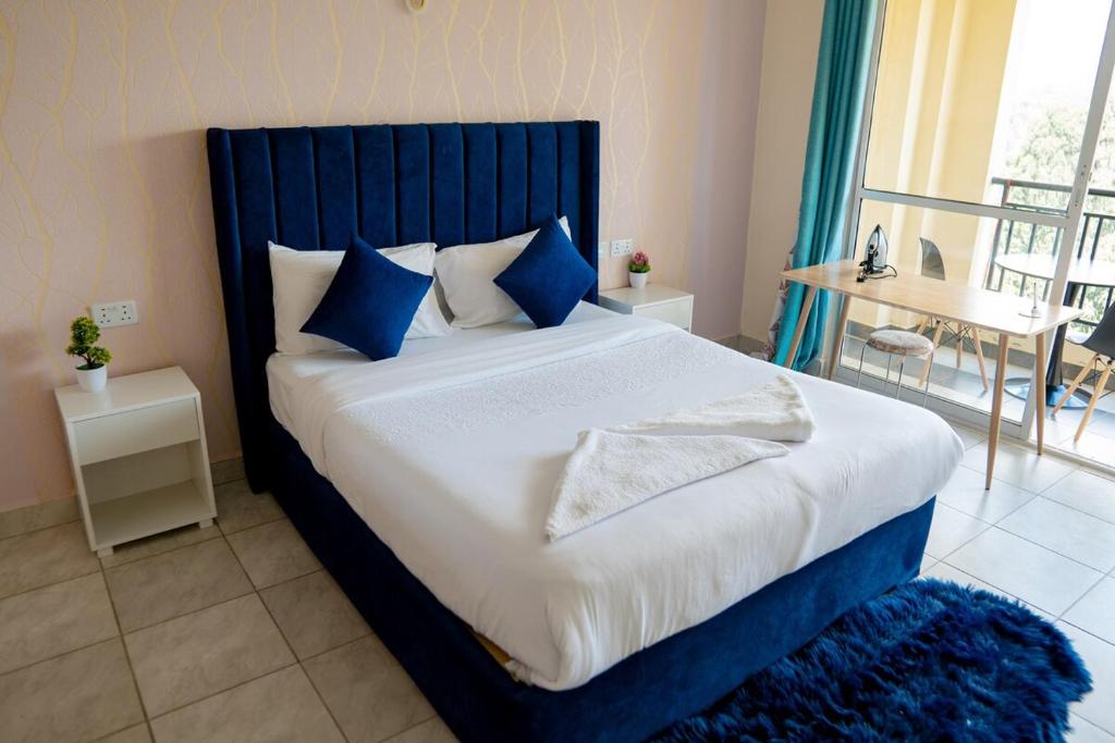 Un dormitorio con una cama grande con cabecero azul. en Sunshine Home, en Nanyuki