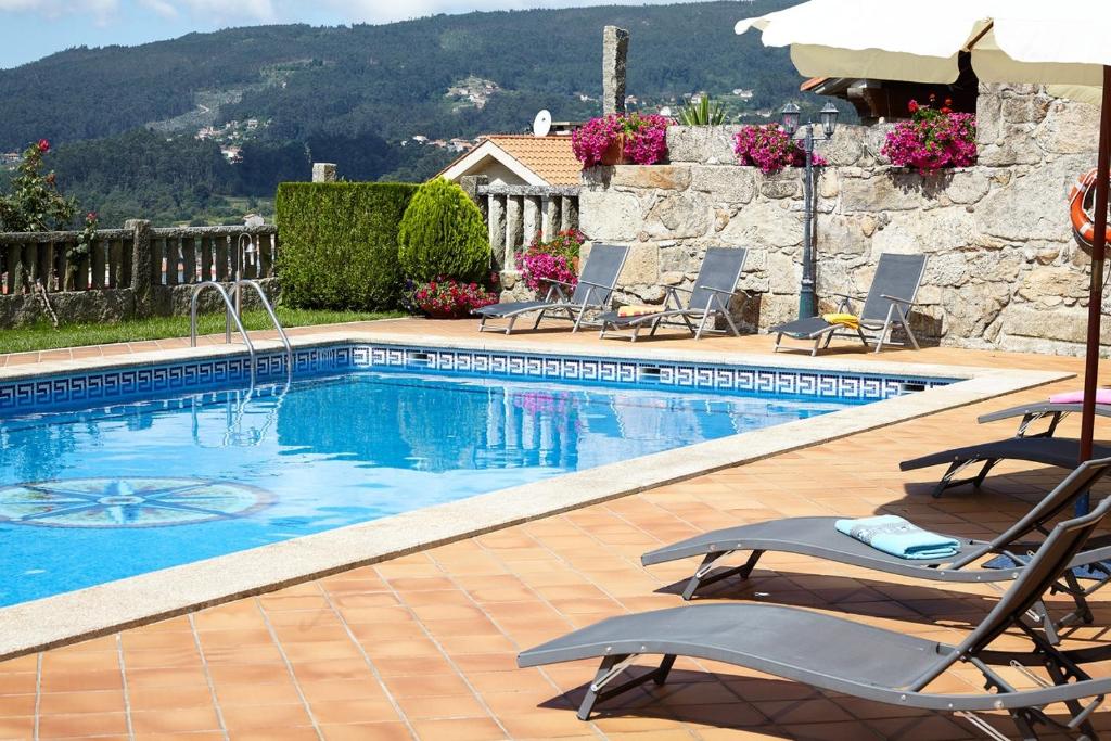 una piscina con sillas y sombrilla en Hotel Liñares, en Poio