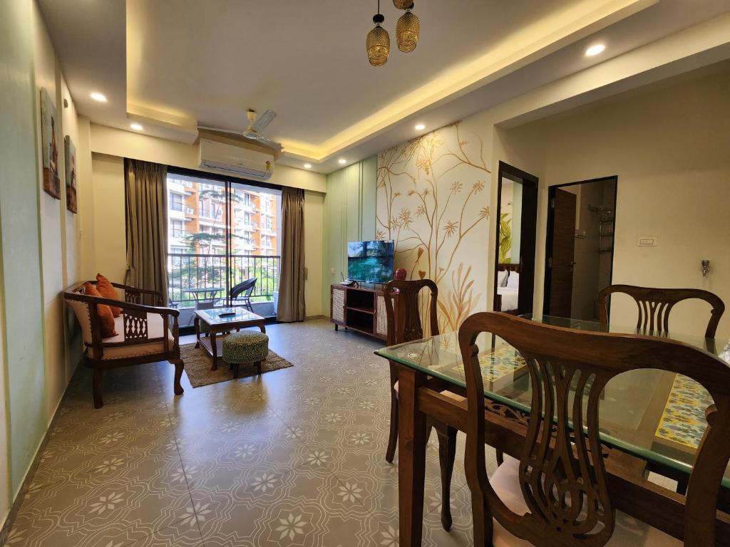 a living room with a table and chairs and a dining room at Bright Candolim 1BHK with Pool, Gym, Parking - 5 Minutes to Beach in Candolim