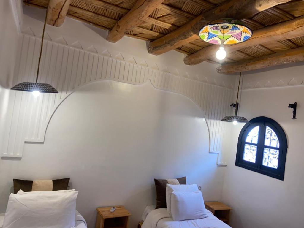 two beds in a room with a window at Hotel Atlas Gorge Dades in Boumalne
