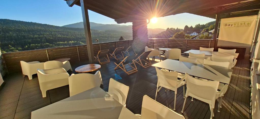 a balcony with white tables and chairs and the mountains at BayVista, die Bayerwald Lodge in Lam