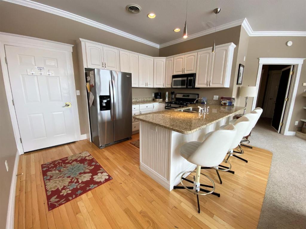 a kitchen with white cabinets and a kitchen island with bar chairs at Pier Harbor #1 in Saint Ignace