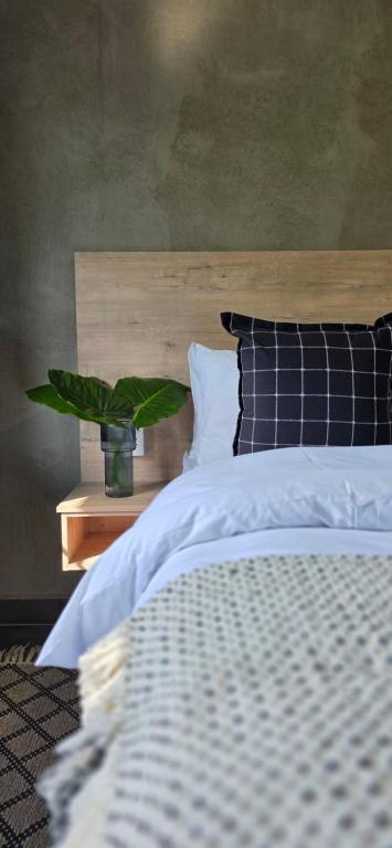 a bedroom with a bed with a plant on a table at Lazél Apartments in Ermelo