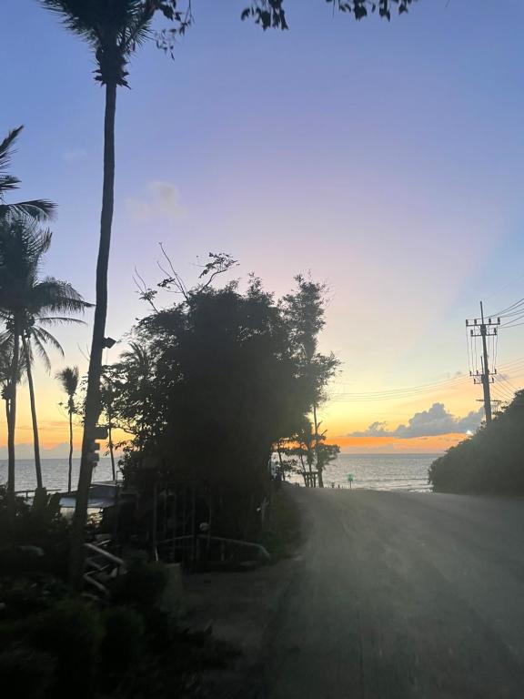 a beach with palm trees and the ocean at sunset at Vannana House Ko Lanta in Ko Lanta