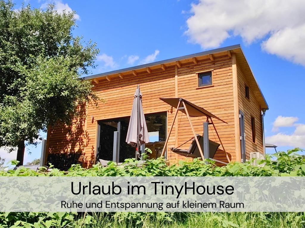 GroßharthauにあるTinyHousebeiDresden unser größtes winziges Häuschen für bis zu 7 Personen, Kaminofen, große Terrasse - Nähe Sächsische Schweiz - Von Juni - September Mindestmietzeit 1 Woche Sa-Saの傘を前に置いた木造家屋