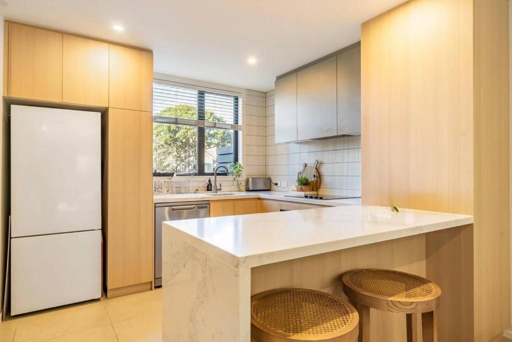a kitchen with a large white counter and stools at The Petone Beauty - Flash, Beachside in Lower Hutt
