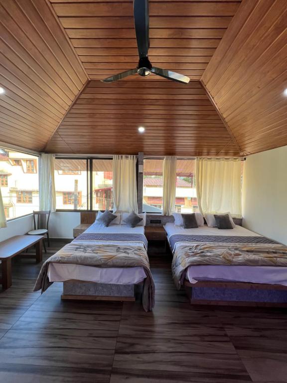 a room with three beds and a wooden ceiling at House of Raj in Madikeri
