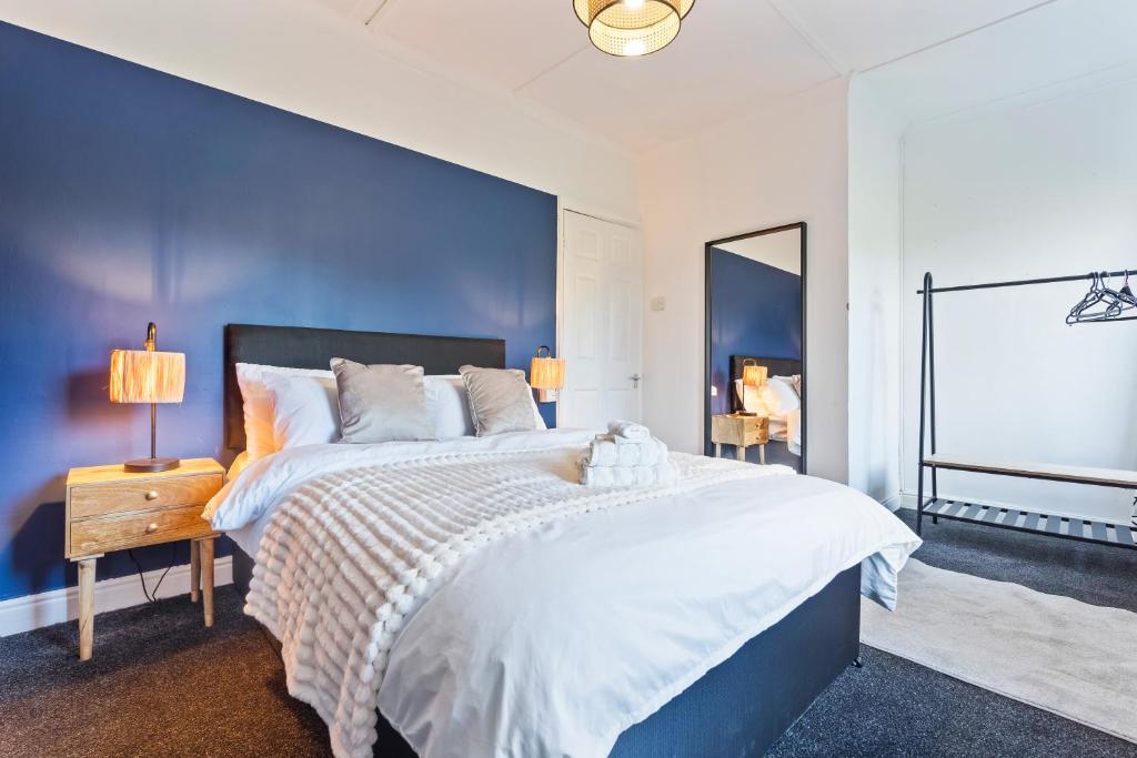 a bedroom with a large bed with a blue wall at Hillview Escape - Group-Friendly Comfort in Abertillery