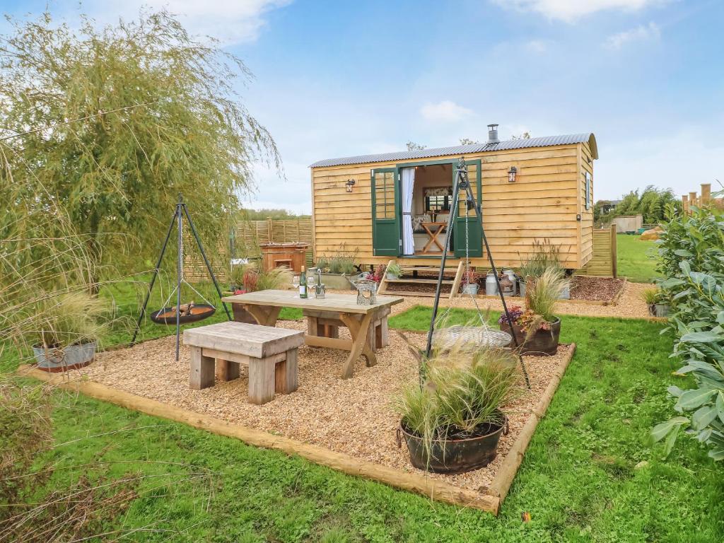 a tiny house with a picnic table and a swing at Poppie's Shepherd Hut - Uk50227 in Redmile