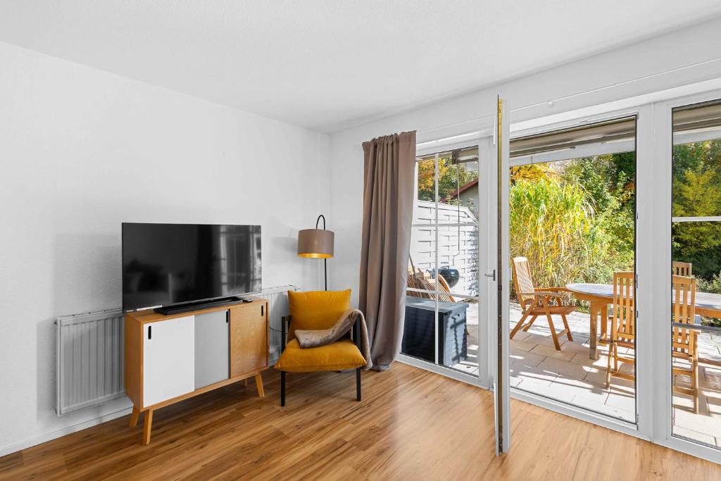 ein Wohnzimmer mit einem TV und einer Glasschiebetür in der Unterkunft EG Apartment - WLAN - Terrasse - Parkplatz in Buchenberg