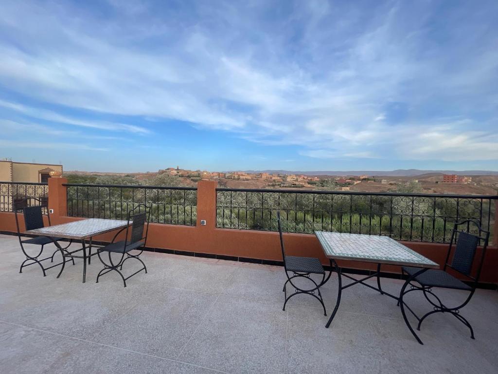 two tables and chairs on a balcony with a view at dar olivegarden inn in Ait Sedrate Sahl Gharbia