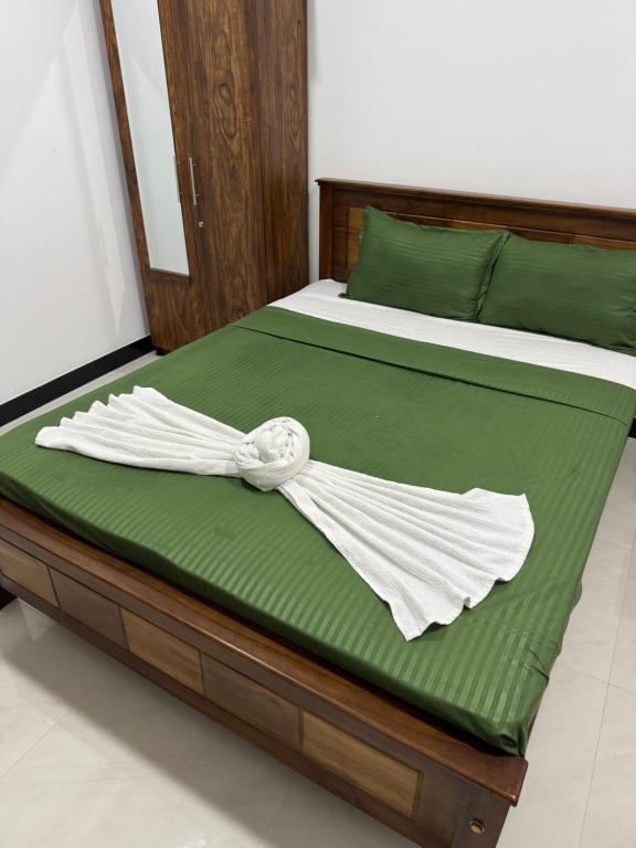 Una cama con sábanas verdes y una toalla blanca encima. en Oceana Luxe, en Negombo