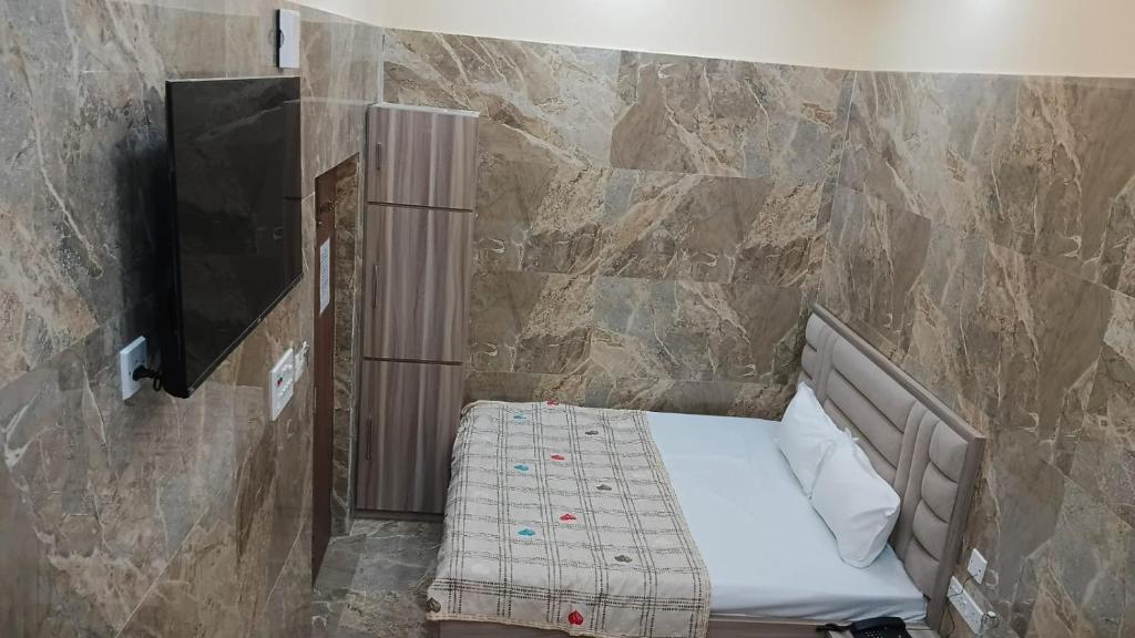 a small bed in a room with a stone wall at Marquis Luxe Guest House in Kolkata