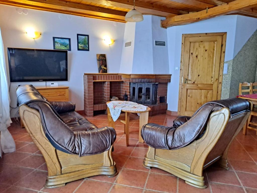 a living room with leather chairs and a fireplace at Domek na Malinowej in Szczyrk