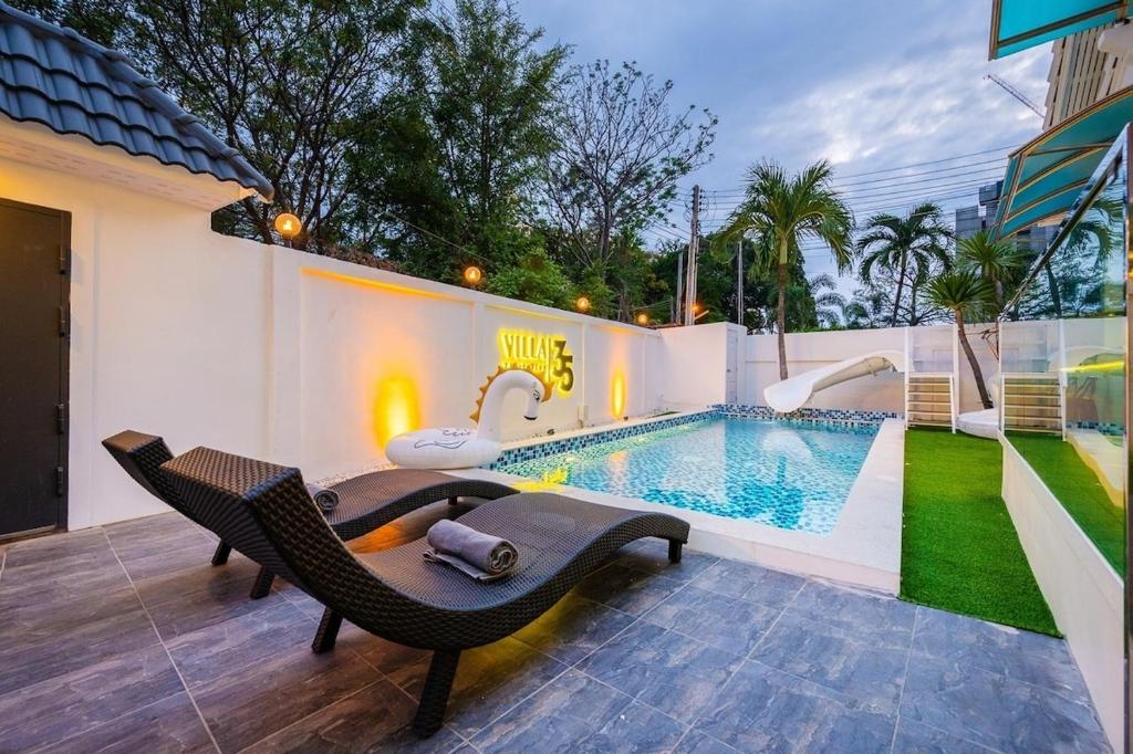 a swimming pool with a bench and a chair next to a house at Villa 35 Wongamat 4BR, 300m from BEACH in North Pattaya