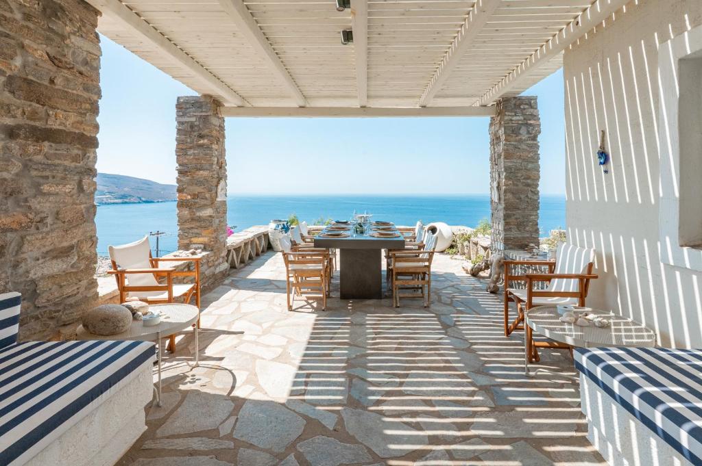 a patio with a table and chairs and the ocean at Villa Néréides in Koundouros