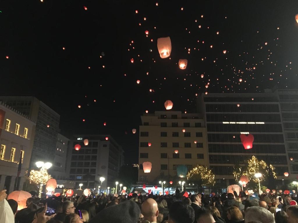 une foule de gens faisant voler des lanternes la nuit dans l'établissement Syntagma Square, à Athènes