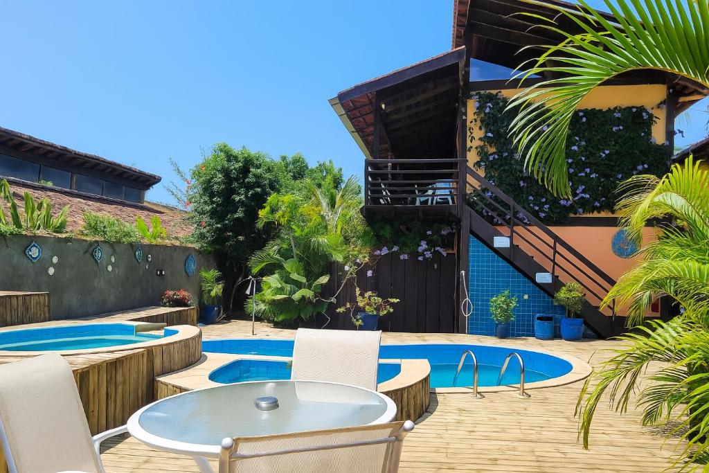 a patio with a table and chairs and a pool at Chalés e Flats Refúgio de Camburi in Camburi