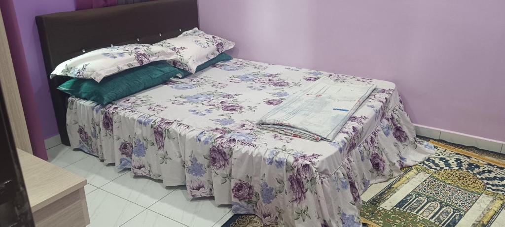 a bed with a blanket and pillows on it at Homestay kak bee d' bendang in Jitra