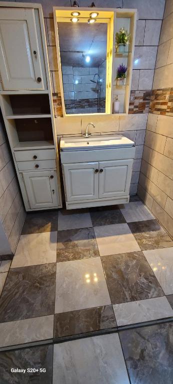 a bathroom with a sink and a tiled floor at Appartement haut standing Mimboman in Yaoundé