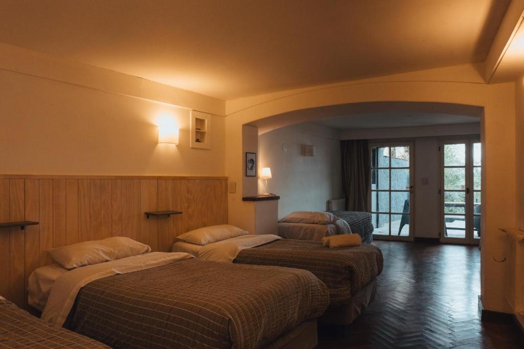 a hotel room with three beds in a room at TEROTERO Lake Hostel - Habitación Mascardi in San Carlos de Bariloche