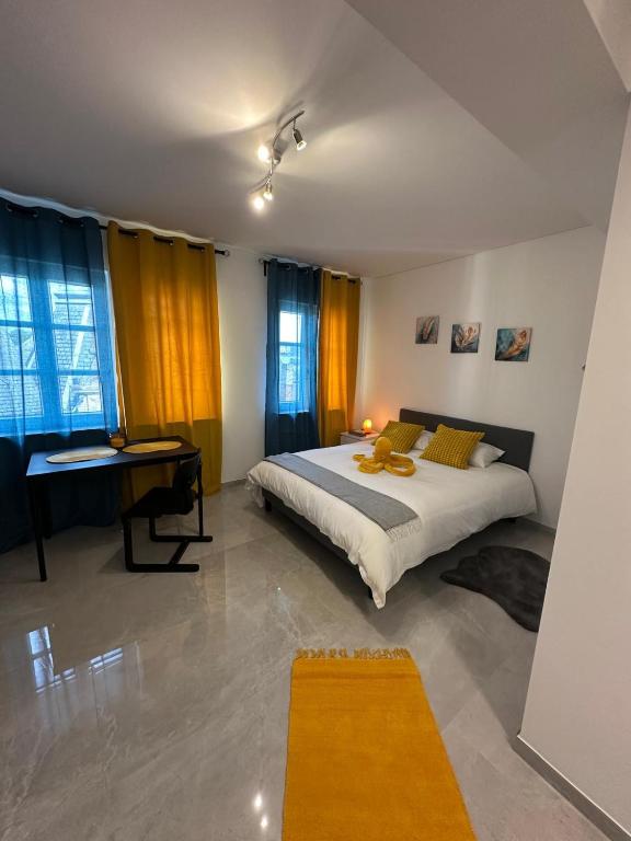 a bedroom with a bed and a desk and windows at Lux City Stays-Beaumont Studio in Luxembourg