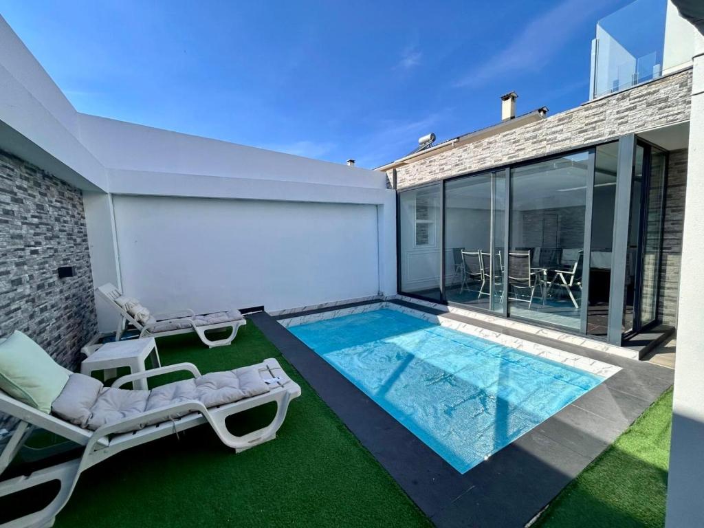 Un patio trasero con piscina y dos tumbonas. en MoradiaT4 com piscina aquecida, en Arrentela