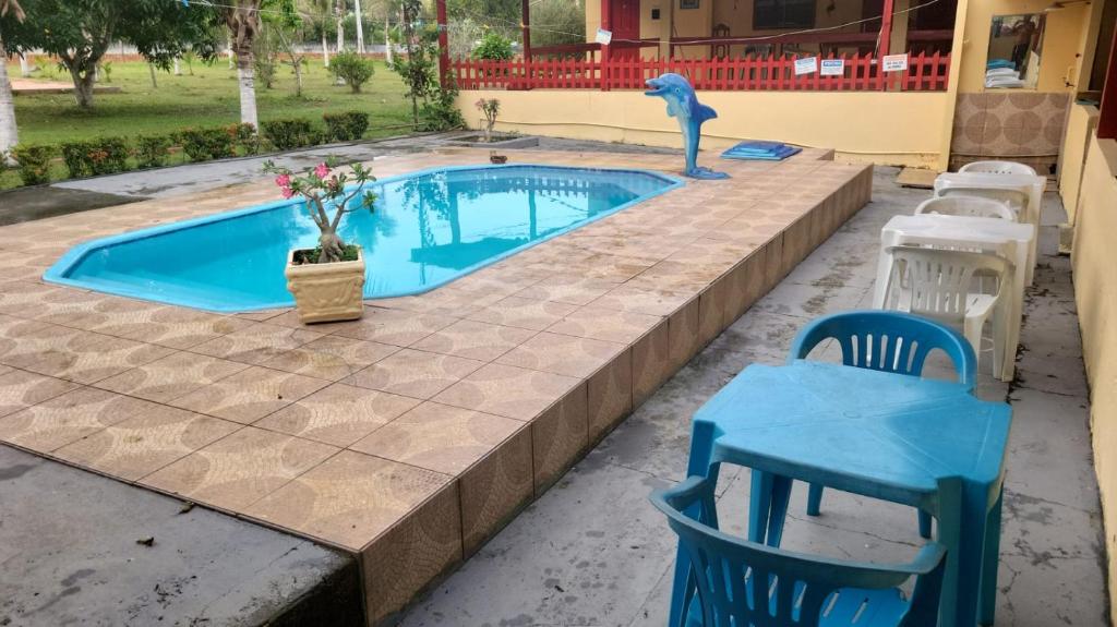a swimming pool with two chairs and a table and a blue shark statue at chacara cheiro da mata in Manacapuru
