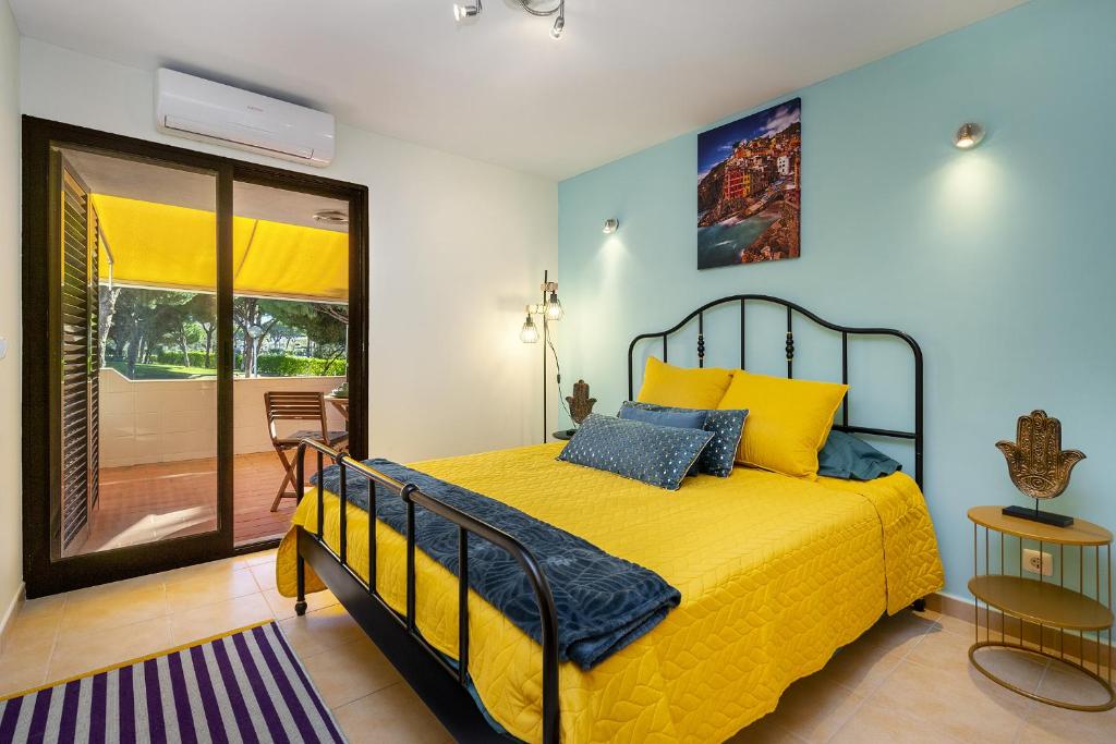 a bedroom with a yellow bed and a balcony at BnB Homes Coastal Pearl Apartment with 2 Pools near to Falesia Beach in Albufeira