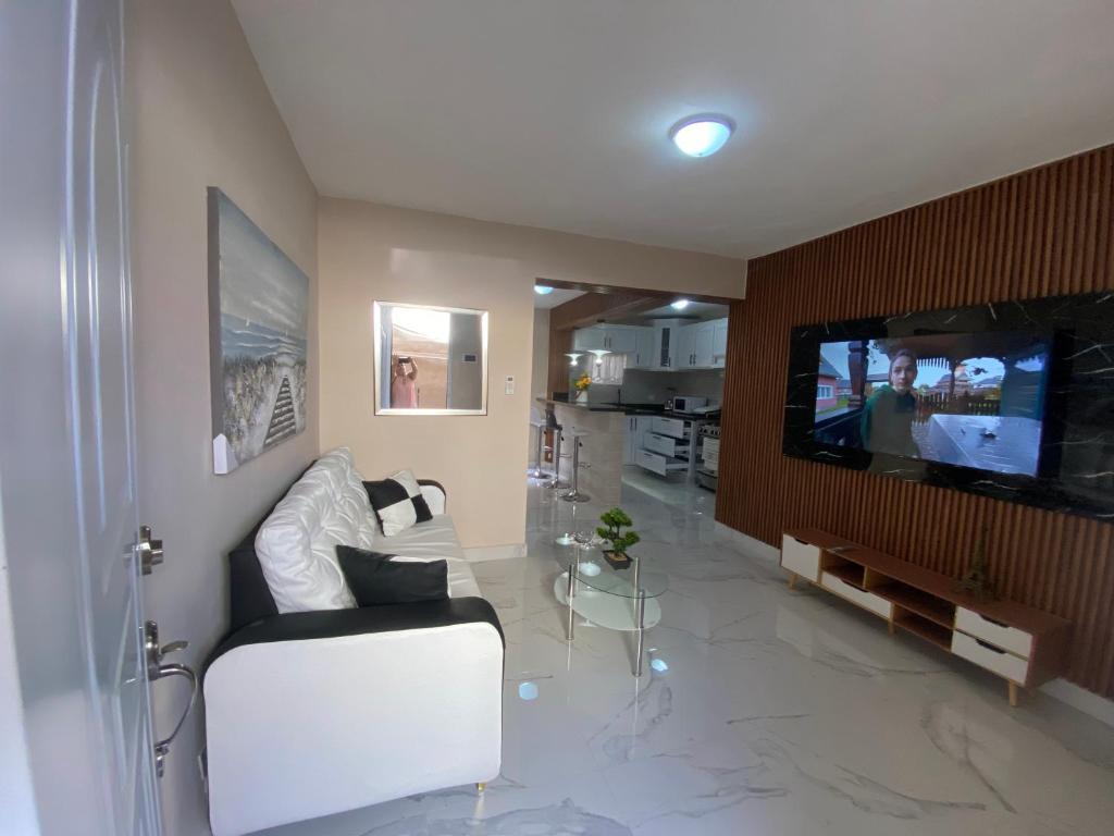 ein Wohnzimmer mit einem weißen Sofa und einem Flachbildfernseher in der Unterkunft apartamento moderno lo mejor de Santiago in Santiago de los Caballeros