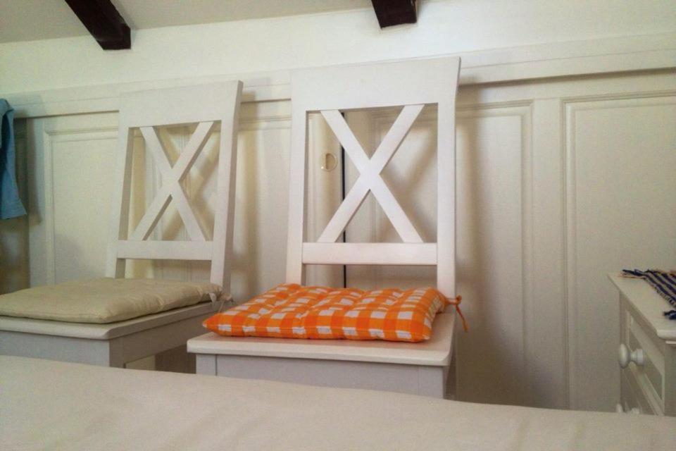 a room with two white chairs with an orange pillow at Villa Agava in Vrboska