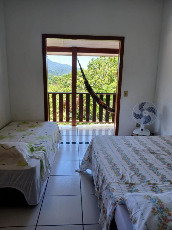 une chambre avec deux lits et une grande fenêtre dans l'établissement Refugio Das Pedras, à Parati
