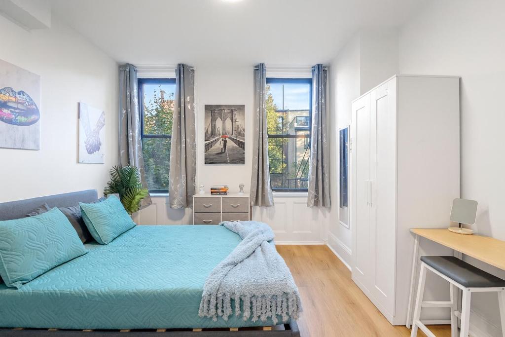 a bedroom with a couch and a desk and windows at 15 Minutes to NYC - Modern & Colorful Hoboken Getaway in Hoboken