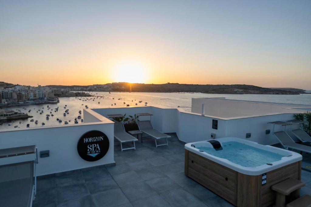 a hot tub on the roof of a building with a beach at HORIZON SUITES by the Sea in St. Paul's Bay