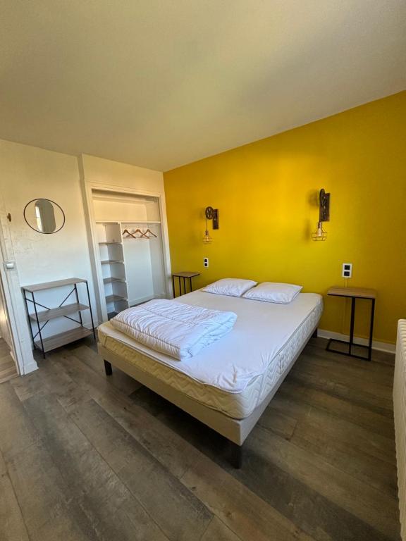 a bedroom with a large bed with a yellow wall at La parenthèse in Clairvaux-les-Lacs