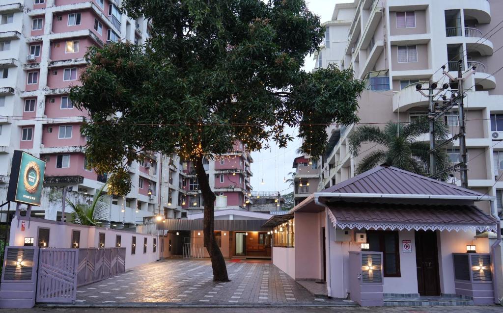 a tree in front of some tall buildings at Guruvayur Nest Homestay in Guruvāyūr