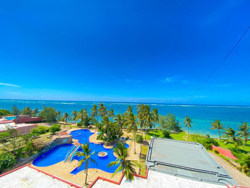 蒙巴萨Mwafrika Beachfront Apartments的享有带游泳池和海洋的度假村的空中景致