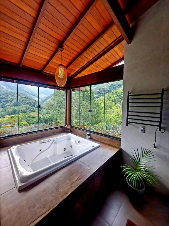 a large bath tub in a room with windows at Recanto Lua de Lumiar in Nova Friburgo