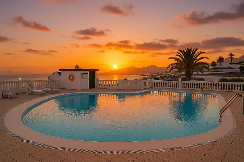 a swimming pool with a sunset in the background at Arthouse Sea View - Acquamarina e Zaffiro in Puerto del Carmen