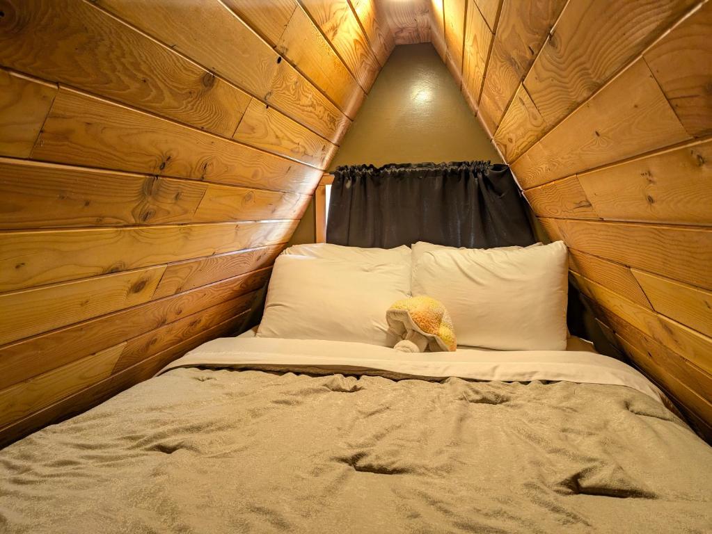 a small bed in a room with a wooden wall at Mushroom theme cabin on 33 Acre Farm in Brew Bay