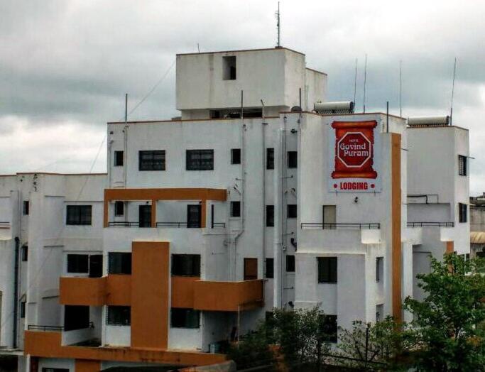 un grande edificio bianco con un'insegna della Coca-Cola sopra di Hotel Govindpuram a Kolhapur