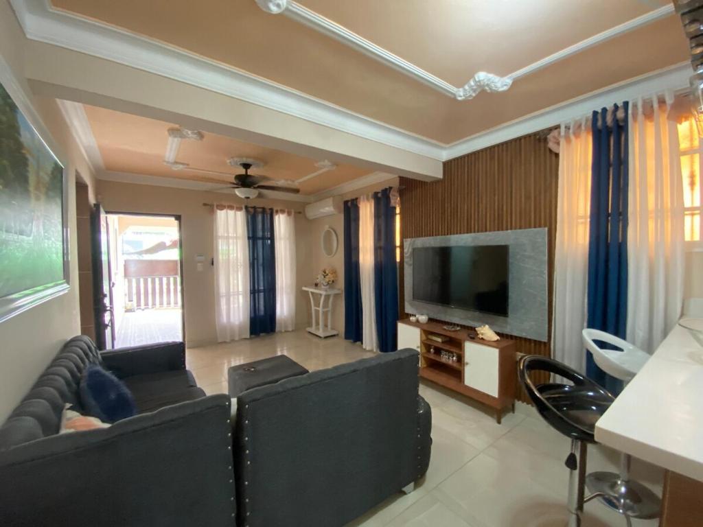 a living room with black leather furniture and a flat screen tv at House in the heart of Santiago in Santiago de los Caballeros