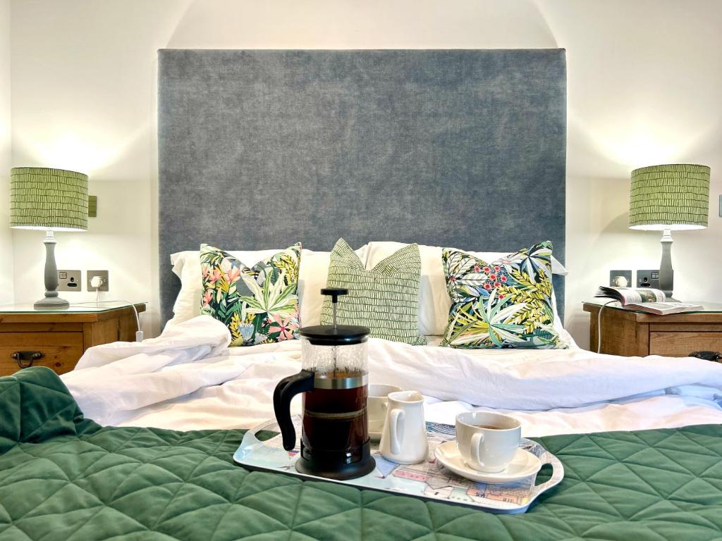 马根波思Merlin Farm Cottages short walk to Mawgan Porth Beach and central location in Cornwall的一张床，上面有一台咖啡机和两个杯子