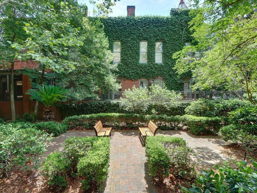 two benches in a garden in front of a building at Charm on Liberty in Savannah