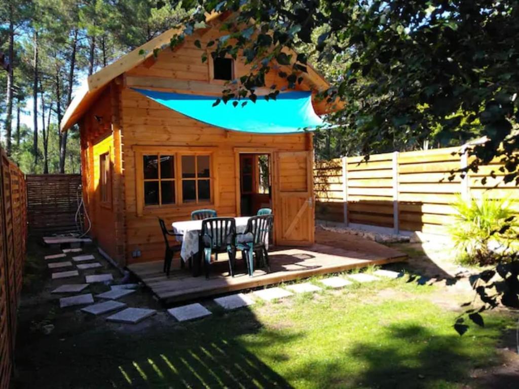 eine Blockhütte mit einem Tisch und Stühlen im Hof in der Unterkunft Chalet en lisiere de Foret in Lacanau