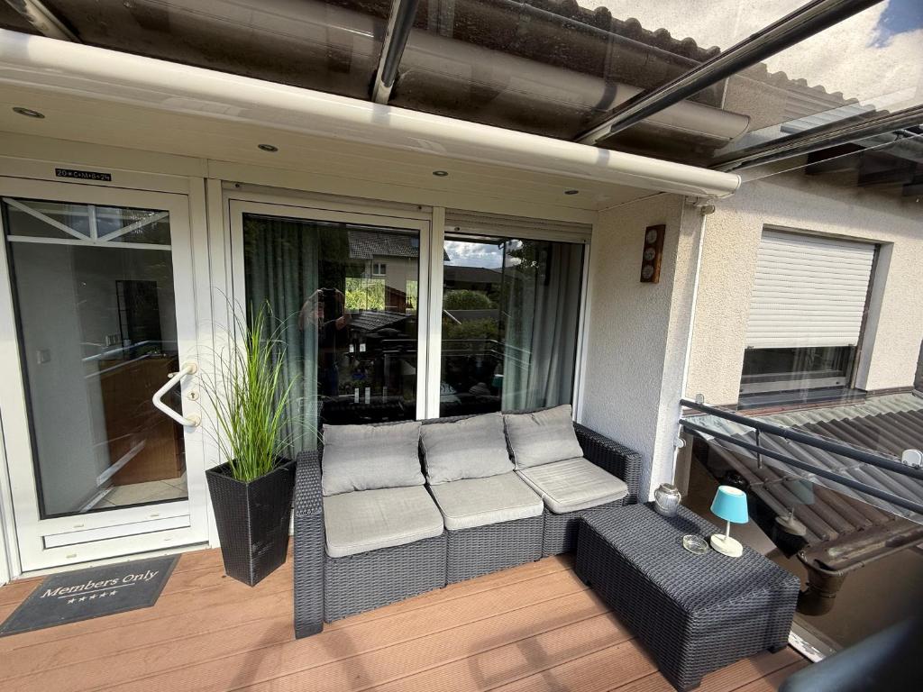a screened in porch with a couch on a patio at Himmelsleiter Ihr Rückzugsort mit Aussicht in Niederfischbach