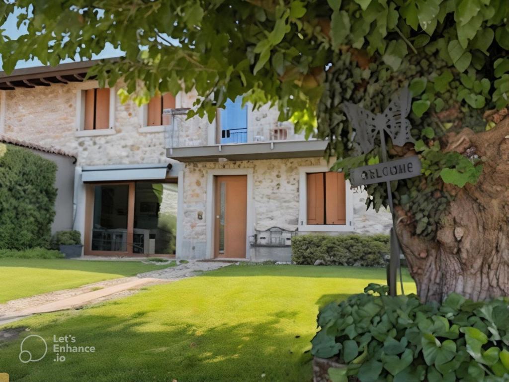 a house with a tree in front of it at Alc&cE' alloggio agrituristico in Povoletto