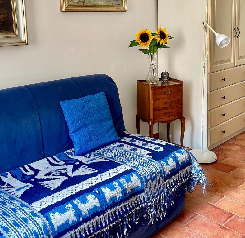 a blue bed in a room with a vase of sunflowers at The window to the sea - a stone's throw from the beach in Genova