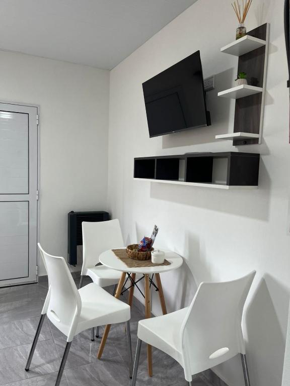 a white dining room with white chairs and a table at Dormis Bajos Medanales in Victorica