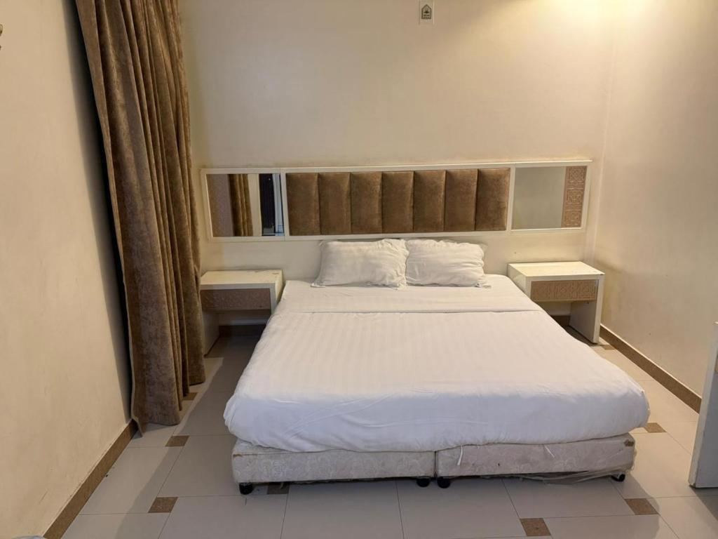 a bedroom with a large bed and two tables at Smart Entry Room Grnada in Riyadh